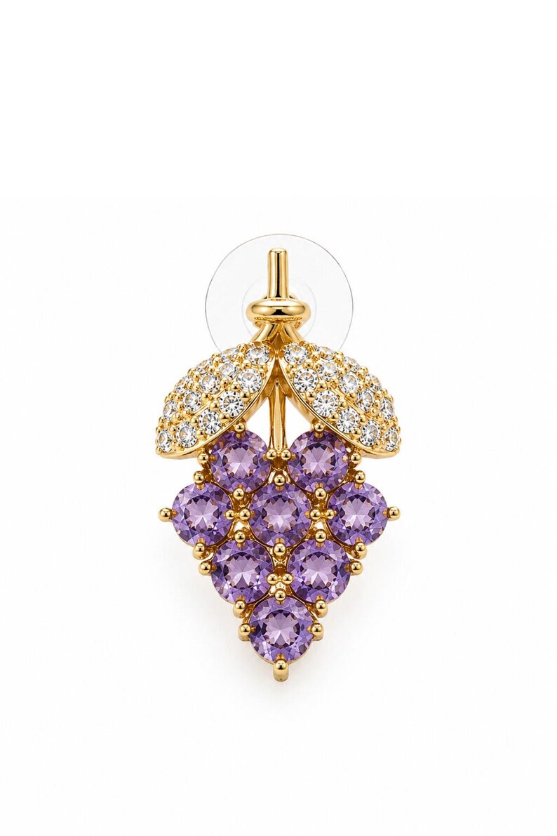 K&ouml;nnte beinhalten: Goldfarbener Ohrring in Form einer Weintraube. Die Trauben werden durch runde, violette Edelsteine dargestellt. Die Bl&auml;tter sind mit kleinen, klaren Edelsteinen besetzt. Der Ohrringstift ist sichtbar.