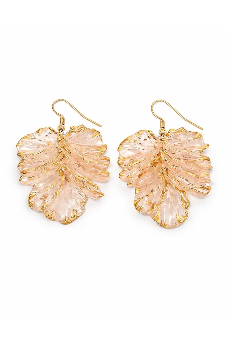 May include: A pair of leaf-shaped earrings. The earrings feature a light pink, translucent design with gold-colored trim. The earrings have a hook closure and are set against a white background.