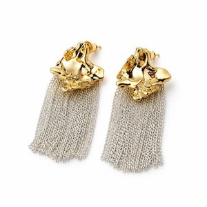 May include: A pair of gold-colored earrings with a textured, organic design. Each earring features a cascade of silver-colored chain fringe, creating a striking contrast. The earrings are presented against a clean white background.