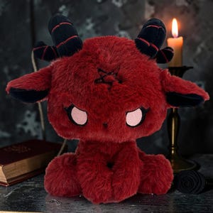 May include: A plush red goat with black horns and ears, and a pentagram on its forehead. The stuffed animal has pink eyes and is sitting down. The plush toy is a unique gothic-themed item.