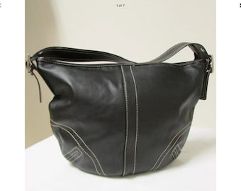 May include: A black leather hobo bag with white stitching. The bag has a single strap and a buckle closure.