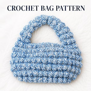 May include: A crochet bag pattern featuring a blue and white variegated yarn with a textured bobble stitch design. The bag has a rounded shape with a single integrated handle. The text CROCHET BAG PATTERN is displayed in dark blue at the top.