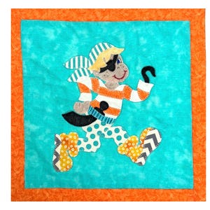 Op de afbeelding: Een kleurrijk stoffen kunstwerk met een cartoonpiraat met een ooglapje en een haakhand. De piraat draagt een gestreept shirt, een broek met stippen en laarzen met patronen. Het kunstwerk is geplaatst tegen een turquoise achtergrond met een oranje rand.