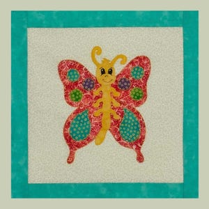 May include: A colorful butterfly applique on a square fabric block. The butterfly has red and teal wings with yellow accents and a smiling face. The block is framed by a teal border and set against a light background.