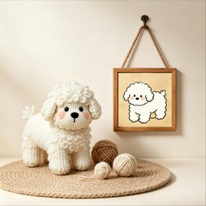 Peut inclure: Une figurine de chien crochetée blanche avec une texture bouclée, des yeux noirs et un nez noir, accompagnée de trois pelotes de laine et d'un cadre mural en bois carré présentant une illustration de chien blanc sur fond beige clair.