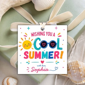 Peut inclure: Une étiquette cadeau carrée avec le texte "Wishing you a Cool Summer !" présente un soleil souriant et des lunettes de soleil avec des verres en forme de cœur. L'étiquette est personnalisée avec le nom "Sophia" et est attachée à un coffret cadeau avec un ruban.