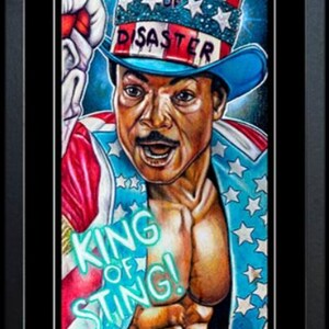 May include: Framed artwork depicting a boxer in patriotic colours. The image includes the word "CREED" in flames, and the phrase "KING OF STING!" is visible. The boxer wears a hat that says "THE MASTER OF DISASTER". The image also says "I WANT YOU".