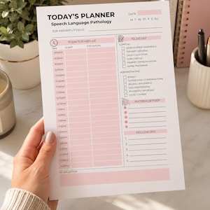Peut inclure: Un planificateur rose et blanc intitulé "Today's Planner" pour l'orthophonie. Le planificateur comprend des sections pour la planification, les listes de tâches et les suivis. Le planificateur est tenu par une personne.