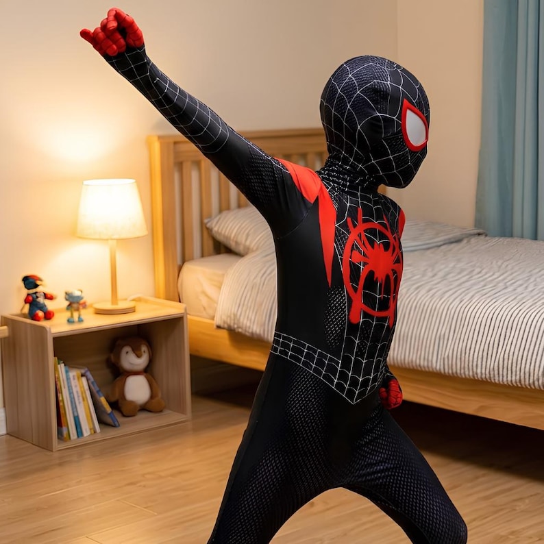 Puede incluir: Un disfraz de Spider-Man negro y rojo con un patr&oacute;n de telara&ntilde;a, un emblema de ara&ntilde;a rojo y una m&aacute;scara. El disfraz lo lleva una persona con el brazo levantado. El disfraz es un traje completo.