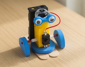May include: A small, handmade robot toy with a yellow body, blue wheels, and googly eyes. The robot has a black battery pack and a red wire connecting the components. It is constructed on a base of wooden craft sticks.