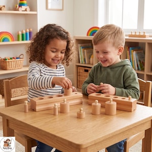 May include: Two light-colored wooden cylinder block sets with matching holes, featuring various sizes of cylindrical pegs. The blocks are placed on a wooden table, with several loose wooden cylinders of differing heights and diameters scattered around the base.