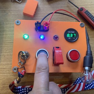 Może przedstawiać: Pomarańczowy elektroniczny panel sterowania z cyfrowym wyświetlaczem napięcia pokazującym 8,37 DC. Panel posiada r&oacute;żne przyciski, przełączniki i wskaźniki, w tym zielone i niebieskie diody LED. Palec naciska przycisk.