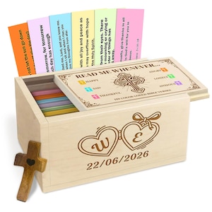Peut inclure: Une boîte en bois avec un couvercle à charnière, contenant des versets bibliques codés par couleur. Le couvercle est décoré d'une croix et des mots "READ ME WHENEVER..." et "150 COLOR CODED BIBLE VERSES". La boîte a une croix en bois sur le côté et deux cœurs avec les lettres "W" et "E" et la date "22/06/2026".
