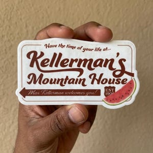 May include: A rectangular sticker with a brown and white design. The sticker reads "Kellerman's Mountain House" with the text "Have the time of your life at..." and "Max Kellerman welcomes you!" A watermelon slice is on the right.