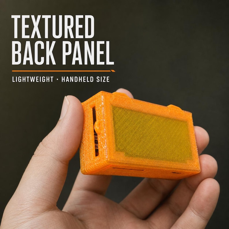 May include: A bright orange rectangular handheld device featuring a textured back panel. The text "TEXTURED BACK PANEL" and "LIGHTWEIGHT - HANDHELD SIZE" is printed in white above the object. The device has a central recessed rectangular area.