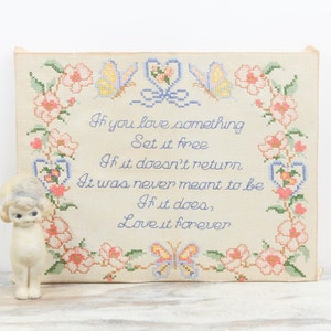 May include: A framed cross-stitch with a white background and a floral border. The cross-stitch features a poem that reads: "If you love something set it free. If it doesn't return it was never meant to be. If it does, love it forever."