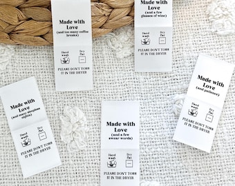 May include: Five white fabric labels with black text and icons. Each label reads "Made with Love" followed by a phrase in parentheses, such as "(and too many coffee breaks)" or "(and a few swear words)". The labels also include instructions for hand washing and drying flat, and a warning to avoid putting the item in the dryer.