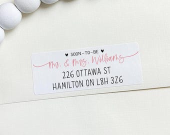 May include: A white and black address label with the text "SOON-TO-BE" and "Mr. & Mrs. Williams" in pink script. The address is "226 OTTAWA ST HAMILTON ON L8H 326".