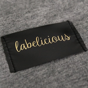 May include: A black fabric label with gold lettering that reads "labelicious".