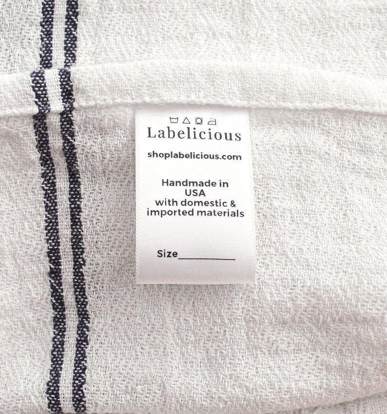 Pode incluir: Etiqueta de tecido branco com texto preto que diz "Labelicious shoplabelicious.com Feito &agrave; m&atilde;o nos EUA com materiais nacionais e importados Tamanho" com uma linha em branco para o tamanho.