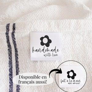 May include: White fabric with a black and white handmade label that says "handmade with love". The label has a black flower with a white center. The fabric has two blue stripes. A second label is shown with the text "fait à la main avec amour" in French.