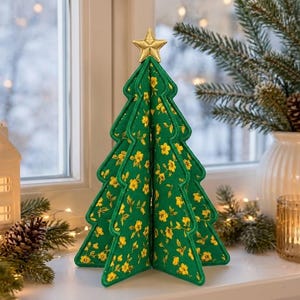 May include: A three-dimensional fabric Christmas tree decoration featuring a vibrant green background with a repeating yellow floral pattern. The tree is topped with a small, gold-colored star and has stitched edges defining its layered shape.
