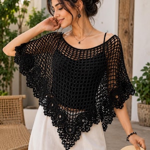 May include: A black crochet poncho featuring an open grid pattern and a decorative scalloped border with circular motifs. The garment is worn over a solid black camisole and paired with light-colored trousers, creating a layered look.
