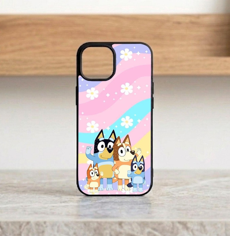 Pu&ograve; includere: Custodia per telefono nera con un design a cartoni animati di famiglia su uno sfondo pastello a strisce rosa, blu e gialle e accenti floreali bianchi. La custodia ha un bordo nero e un ritaglio per la fotocamera.