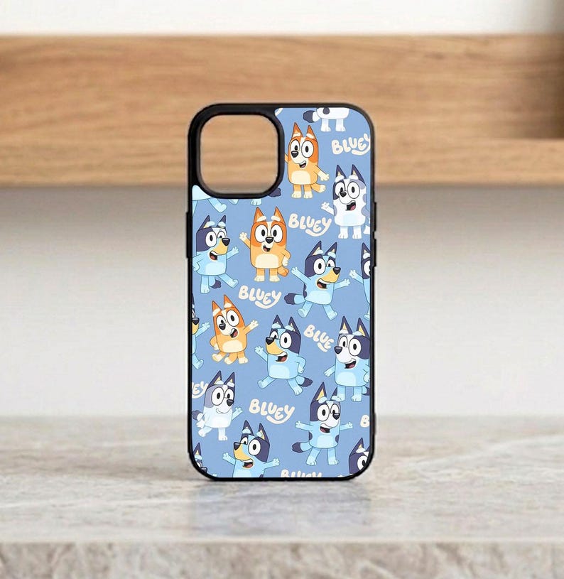 Pu&ograve; includere: Custodia per telefono nera con un motivo ripetuto di cani dei cartoni animati su sfondo azzurro. La parola "Bluey" &egrave; stampata sulla custodia. La custodia ha un ritaglio per la fotocamera e un bordo nero.