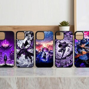 Op de afbeelding: Vijf zwarte telefoonhoesjes met kleurrijke fantasy art designs. De hoesjes tonen afbeeldingen van personages, draken en landschappen in tinten paars, blauw en wit. De hoesjes worden getoond op een houten oppervlak.
