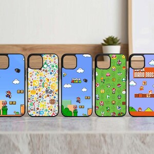 Può includere: Cinque custodie per telefono con cornice nera con disegni colorati di Super Mario Bros. Ogni custodia presenta una scena o un motivo diverso del videogioco classico, inclusi personaggi, livelli e il logo del gioco.