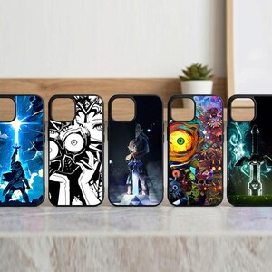 May include: Five black phone cases with different designs. The cases feature artwork from a video game series. The designs include a character silhouetted against a blue sky, a black and white character, and a sword.