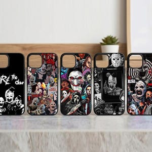 Può includere: Cinque custodie per telefono nere con disegni a tema horror. Le custodie presentano immagini di clown, personaggi di film horror e la scritta "ARE the clown". Le custodie sono esposte su una superficie chiara.