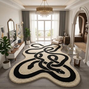 May include: A cream-coloured rug with a black snake design. The rug features intertwined snakes with detailed heads. The room has a modern aesthetic with neutral tones, a large window, and a chandelier. The rug is likely measured in centimetres.