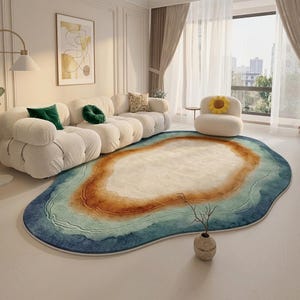 Può includere: Un tappeto di forma ovale irregolare caratterizzato da un design sfumato che passa da un centro color crema a tonalità di marrone caldo, verde acqua chiaro e blu intenso sui bordi, imitando l'aspetto di un paesaggio naturale o d'acqua.