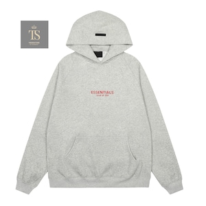 Op de afbeelding: Een lichtgrijze gem&ecirc;leerde hoodie met een capuchon voorzien van een zwarte rechthoekige patch. Op de borst staat de rode tekst ESSENTIALS FEAR OF GOD. Het kledingstuk heeft lange mouwen, een kangoeroezak en boorden aan de mouwen en zoom.