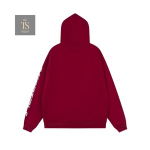 K&ouml;nnte beinhalten: Ein weinroter Kapuzenpullover mit Kapuze und langen &Auml;rmeln. Wei&szlig;er Text ist vertikal am linken &Auml;rmel aufgedruckt. Der Hoodie besteht aus einem weichen Material und eignet sich f&uuml;r Freizeitkleidung.