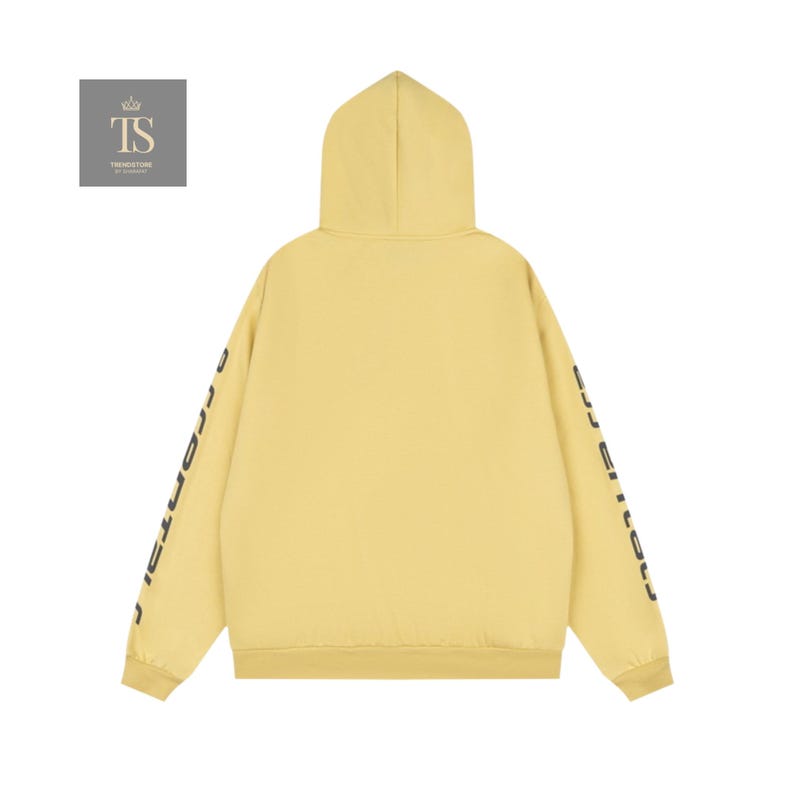 K&ouml;nnte beinhalten: Ein hellgelber Kapuzenpullover mit Kapuze und langen &Auml;rmeln. Die &Auml;rmel haben schwarzen Text. Die R&uuml;ckseite des Kapuzenpullovers ist schlicht. Der Kapuzenpullover ist aus einem weichen Material. Das Logo "TS TRENDSTORE" befindet sich in der oberen linken Ecke.
