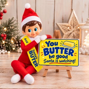 May include: A doll wearing a red suit and hat with a yellow sash labeled 4oz Santa's BUTER, leaning on a wooden easel holding a yellow sign that reads You BUTTER be good Santa is watching! with an illustration of a stick of butter.