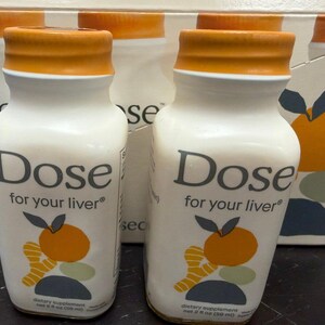 May include: White bottles with orange caps and the text "Dose for your liver" are displayed. Each bottle has a graphic of an orange and ginger. The bottles are dietary supplements, each containing 2 fl oz (59 ml).