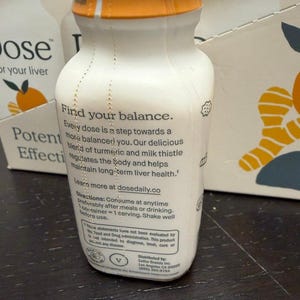 May include: White bottle with an orange cap. The bottle has text that reads "Find your balance" and "Every dose is a step towards a more balanced you." The product is for liver health and contains turmeric and milk thistle.