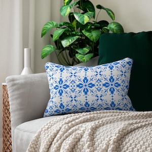 May include: A rectangular throw pillow featuring a white base with a repeating blue floral and vine pattern. The design consists of symmetrical, stylized flower motifs arranged in a grid, creating a continuous decorative print across the surface.