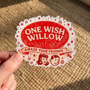 May include: A white-edged sticker with a red oval center featuring the text "ONE WISH WILLOW" in a vintage font. Below, a banner reads "AMAZE YOUR FRIENDS." The sticker includes illustrations of people and stars.
