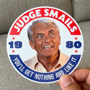 May include: A circular sticker featuring a portrait of Judge Smails with a surprised expression. The text JUDGE SMAILs is arched at the top, 19 and 80 are on the sides, and YOU'LL GET NOTHING AND LIKE IT is arched at the bottom in blue.