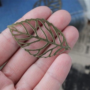 Puede incluir: Una hoja de metal dorado con un diseño delicado e intrincado. La hoja está recortada, creando un efecto de encaje. Es un elemento decorativo que se puede utilizar para manualidades o la elaboración de joyas.