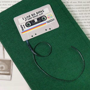 May include: A green book with a cassette tape bookmark. The bookmark has the text "I Like Big Books by Sure-Reads-Alot" and "Chapter 1".
