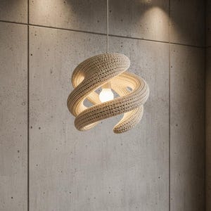 Könnte beinhalten: Eine beige, spiralförmige Pendelleuchte. Das Licht besteht aus einem gewebten Material, mit einer im Zentrum sichtbaren Glühbirne. Die Leuchte hängt an einem weißen Kabel vor einer Betonwand.