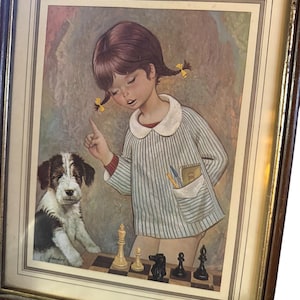 May include: A framed print featuring a young child with brown hair in pigtails wearing a striped shirt with a white collar, standing next to a black and white puppy. The child is gesturing toward a chessboard with several chess pieces arranged.