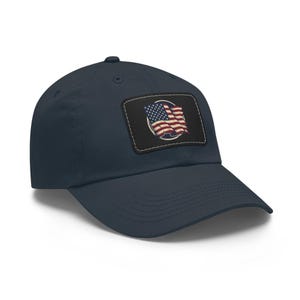 May include: Navy blue baseball cap with a distressed American flag patch. The patch features a vintage-style waving flag in red, white, and blue, set against a black background. A classic, adjustable hat.