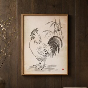 Puede incluir: Pintura a la tinta enmarcada de un gallo en blanco y negro. La obra de arte se exhibe en una pared de madera oscura. Un jarrón con ramas y una pequeña lámpara están en un estante de madera debajo de la pintura. La escena evoca calma.